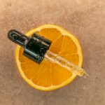 Vitamin C serum dropper on orange — anti-aging skincare routine for women in their 30s