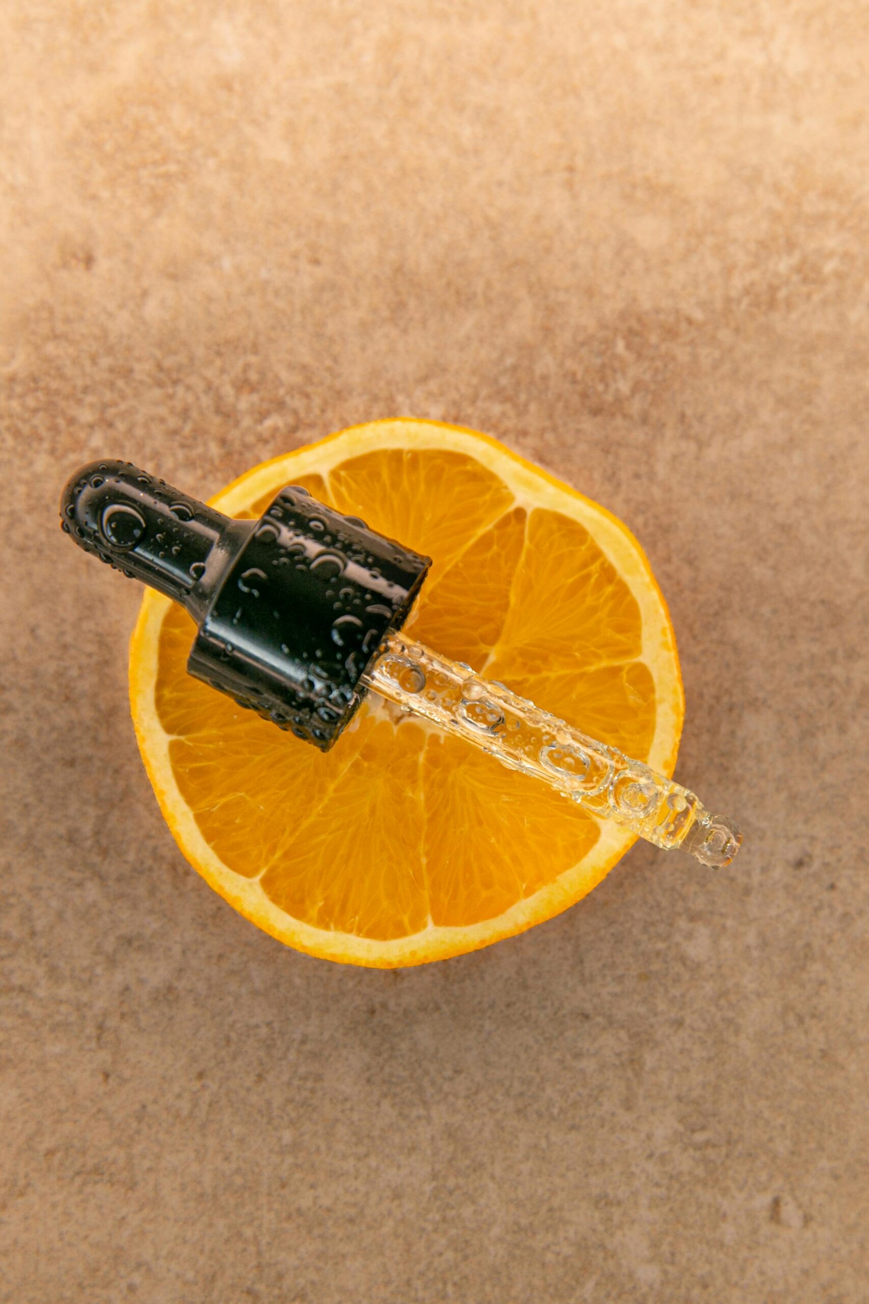 Vitamin C serum dropper on orange — anti-aging skincare routine for women in their 30s