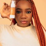 Woman holding a skincare serum bottle in natural light — vitamin C and niacinamide protocol for fading hyperpigmentation in your 30s