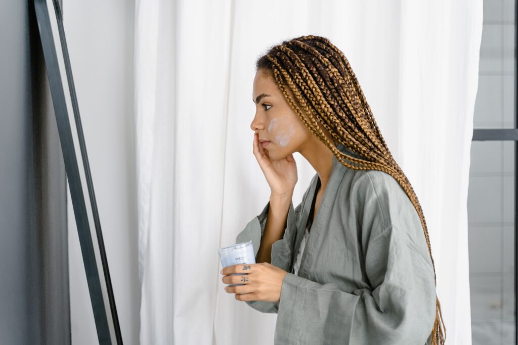Woman applying anti-aging moisturizer in front of mirror as part of her morning skincare routine — best moisturizer for women in their 30s
