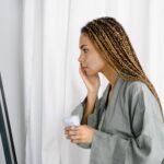 Woman applying anti-aging moisturizer in front of mirror as part of her morning skincare routine — best moisturizer for women in their 30s
